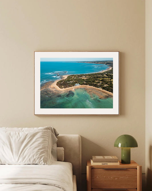 Point Leo Boat Club aerial print in a natural oak frame styled in a bedroom