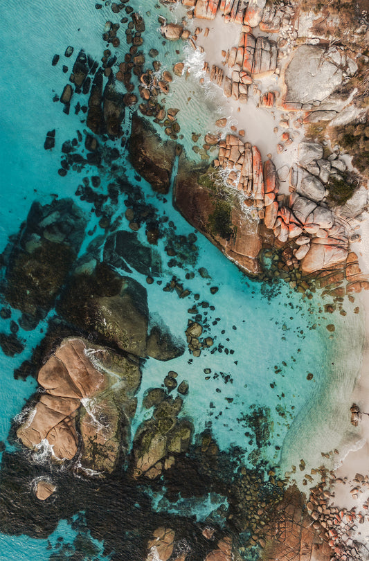 Aerial photo of Bay of Fires Tasmania with orange rocks and clear turquoise water in morning light