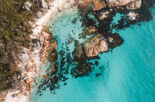Aerial landscape view of Bay of Fires Tasmania with orange boulders and turquoise ocean in early morning light