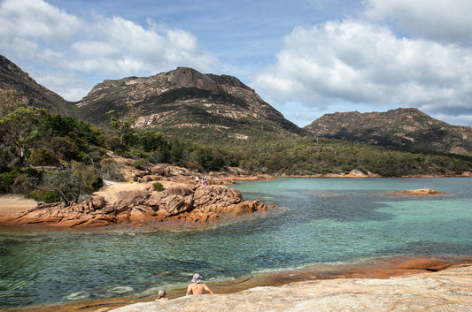 Coastal view of Honeymoon Bay with mountain backdrop and green water