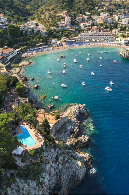 Aerial portrait view of Spiaggia di Mazzarò in Sicily, showcasing the curved coastline, turquoise bay, and surrounding cliffs.