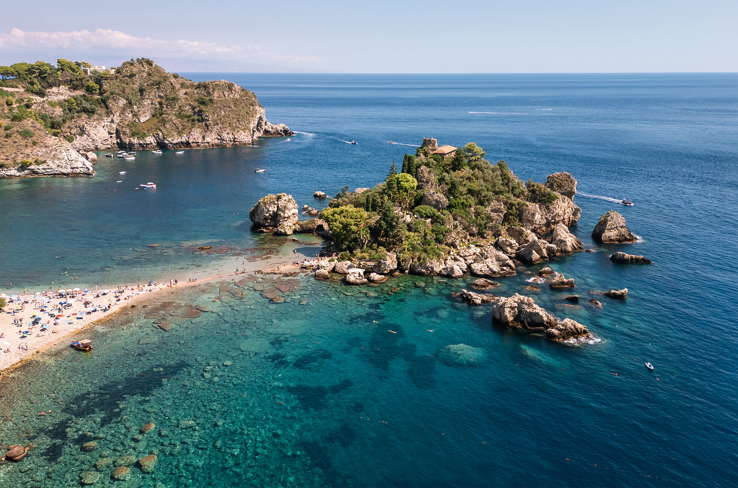Aerial landscape image of Isola Bella Island off the coast of Taormina, Sicily, surrounded by turquoise Mediterranean water.