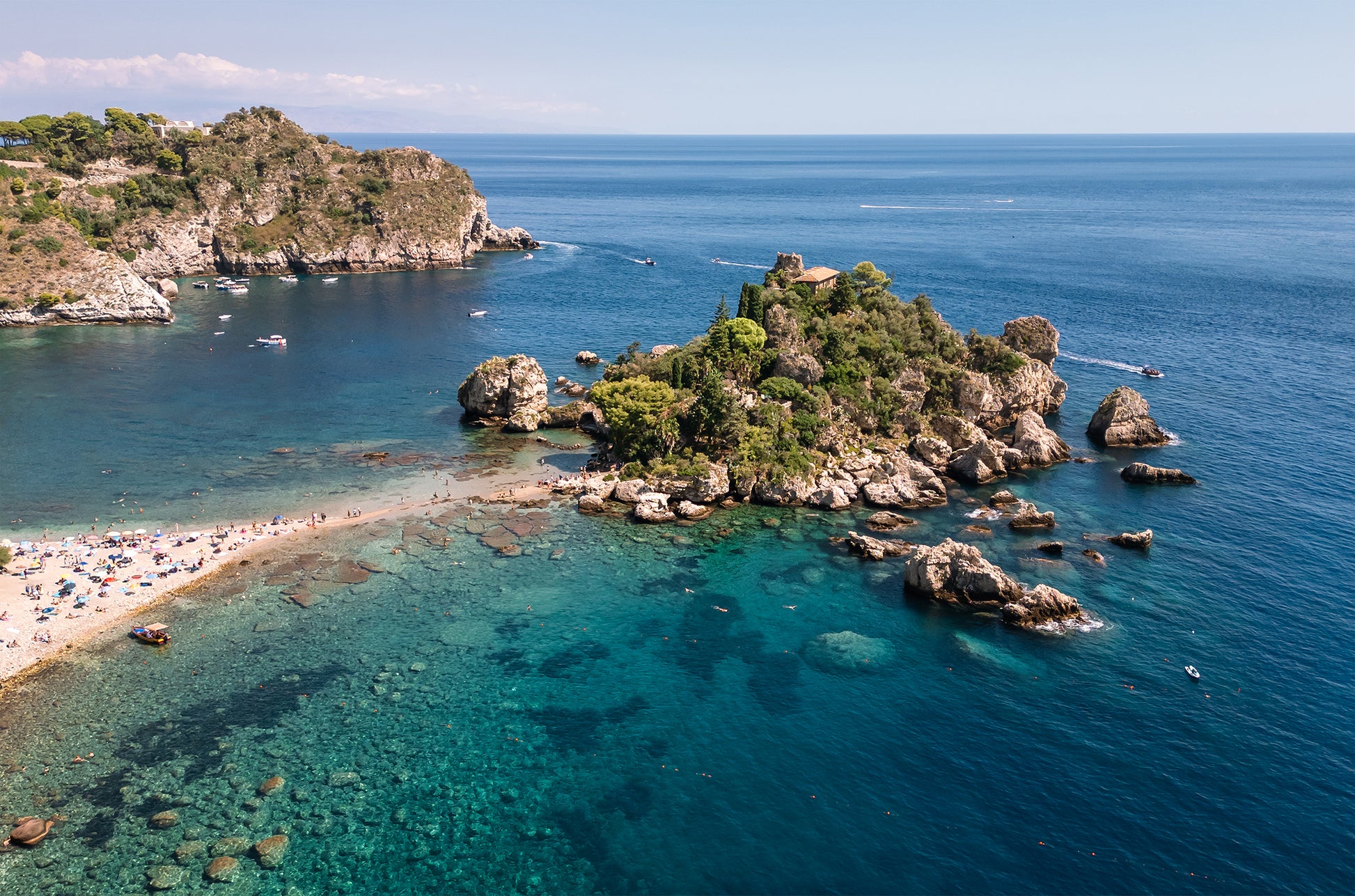 Aerial landscape image of Isola Bella Island off the coast of Taormina, Sicily, surrounded by turquoise Mediterranean water.