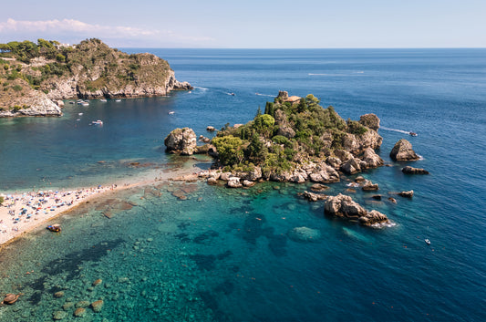 Aerial landscape image of Isola Bella Island off the coast of Taormina, Sicily, surrounded by turquoise Mediterranean water.