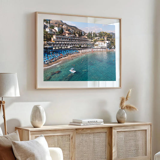 Drone image of an Italian beach resort with umbrellas on golden sand and clear water at Spiaggia Beach, Taormina.