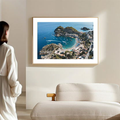 Drone shot of the Taormina coastline showing rich blue water and golden sand at Spiaggia di Mazzarò, captured in wide format.