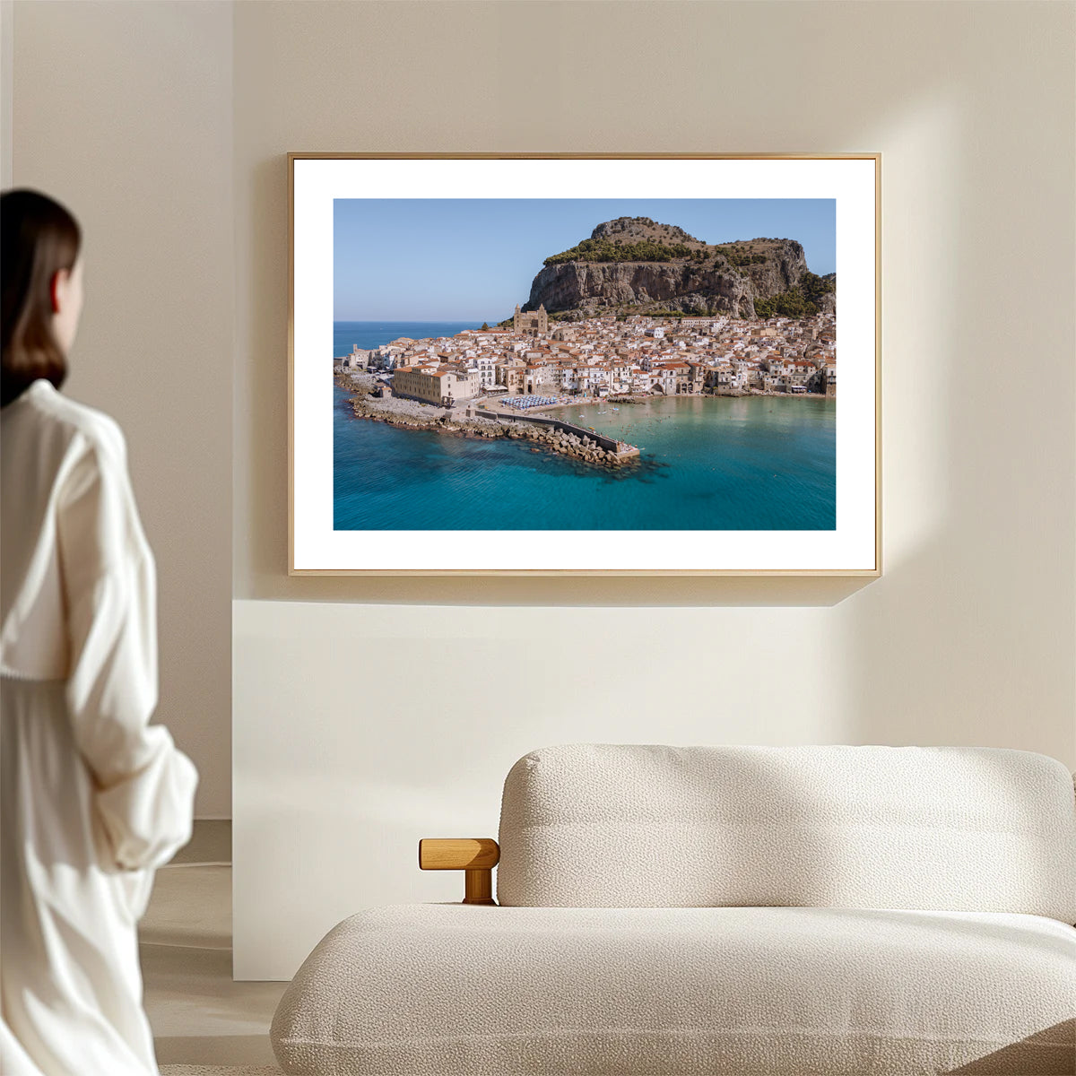 Wide aerial wall art photograph of Cefalù, Sicily showing the old town viewed from the sea with warm city tones and blue water.