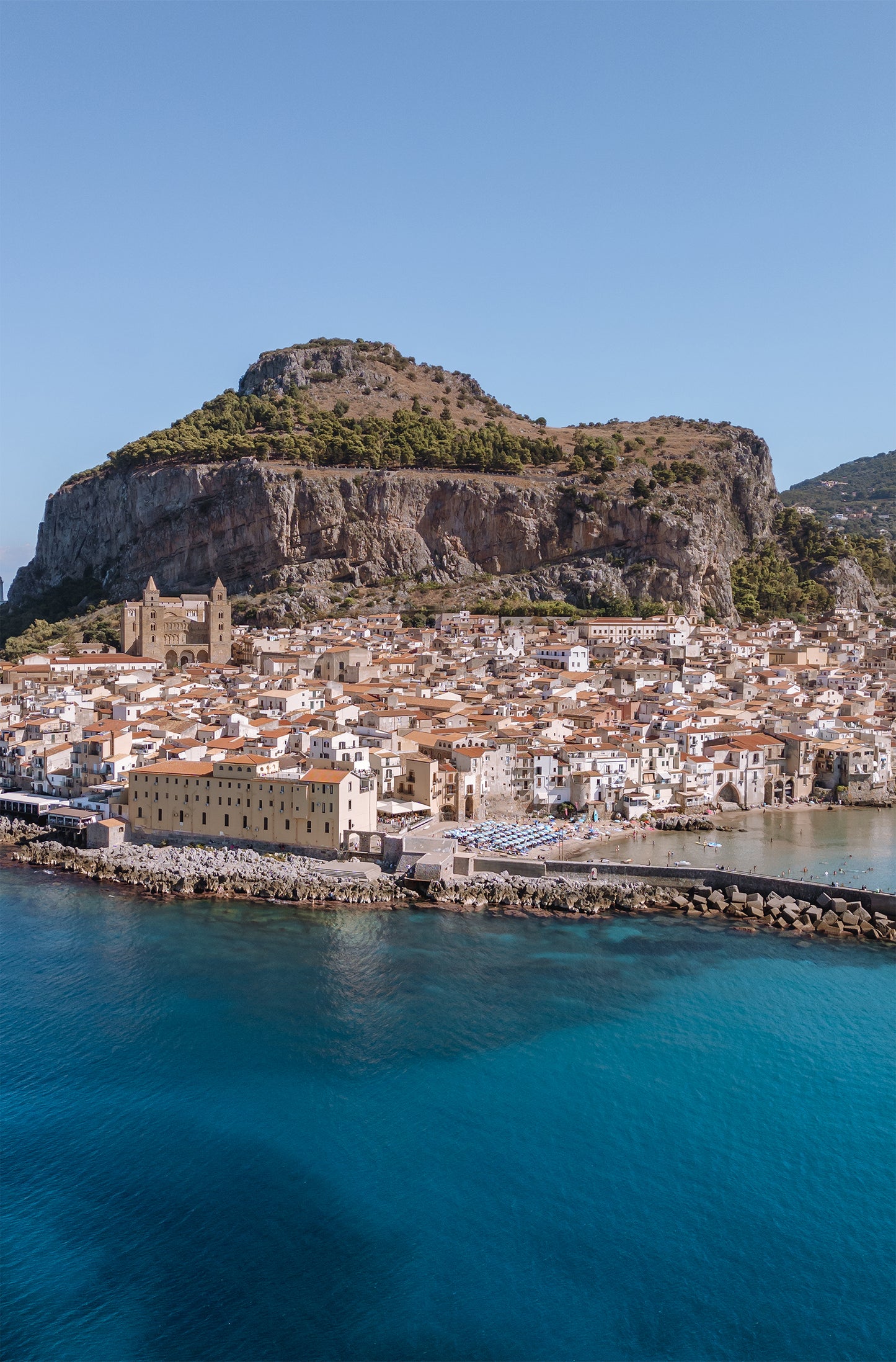 Cefalù Beach Print showing a portrait aerial view of the coastline and Mediterranean waters beside the historic seaside town in Sicily.