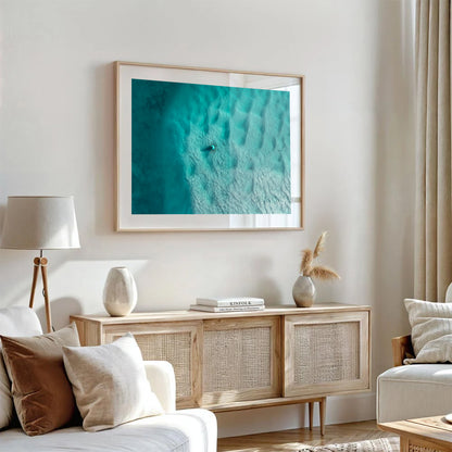Currambene Creek print in a natural oak frame, styled above a rattan sideboard in a warm neutral living room.