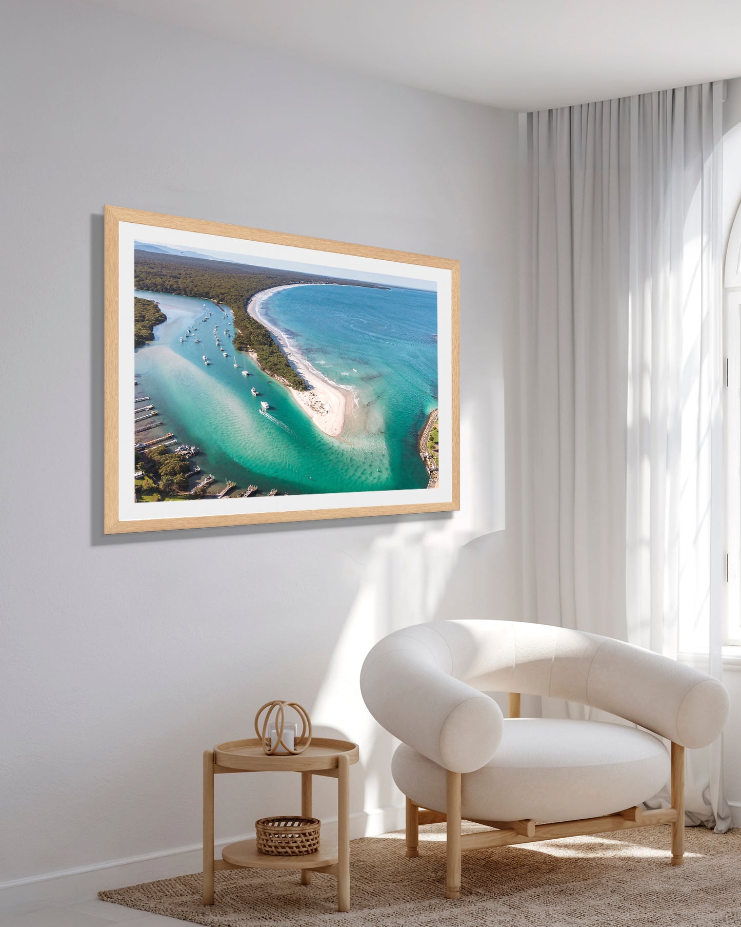 Myola Kite Beach wide print in a natural oak frame, styled above a side table in a bright reading corner with a boucle armchair.