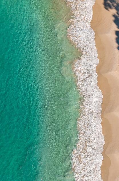 Top-down aerial of Huskisson Beach NSW, with emerald green water, white foaming wave edges and golden sand crossed by tree shadows.