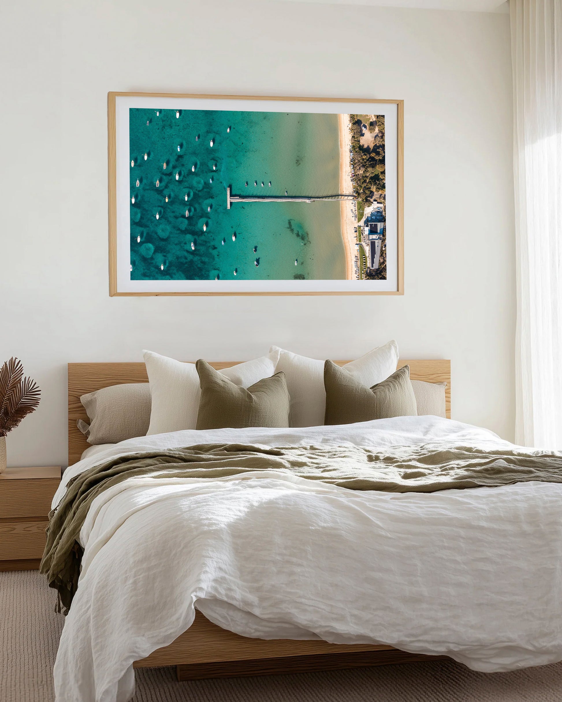 Sorrento Sailing Club print in a natural oak frame, styled above a bed beneath a rattan pendant light.