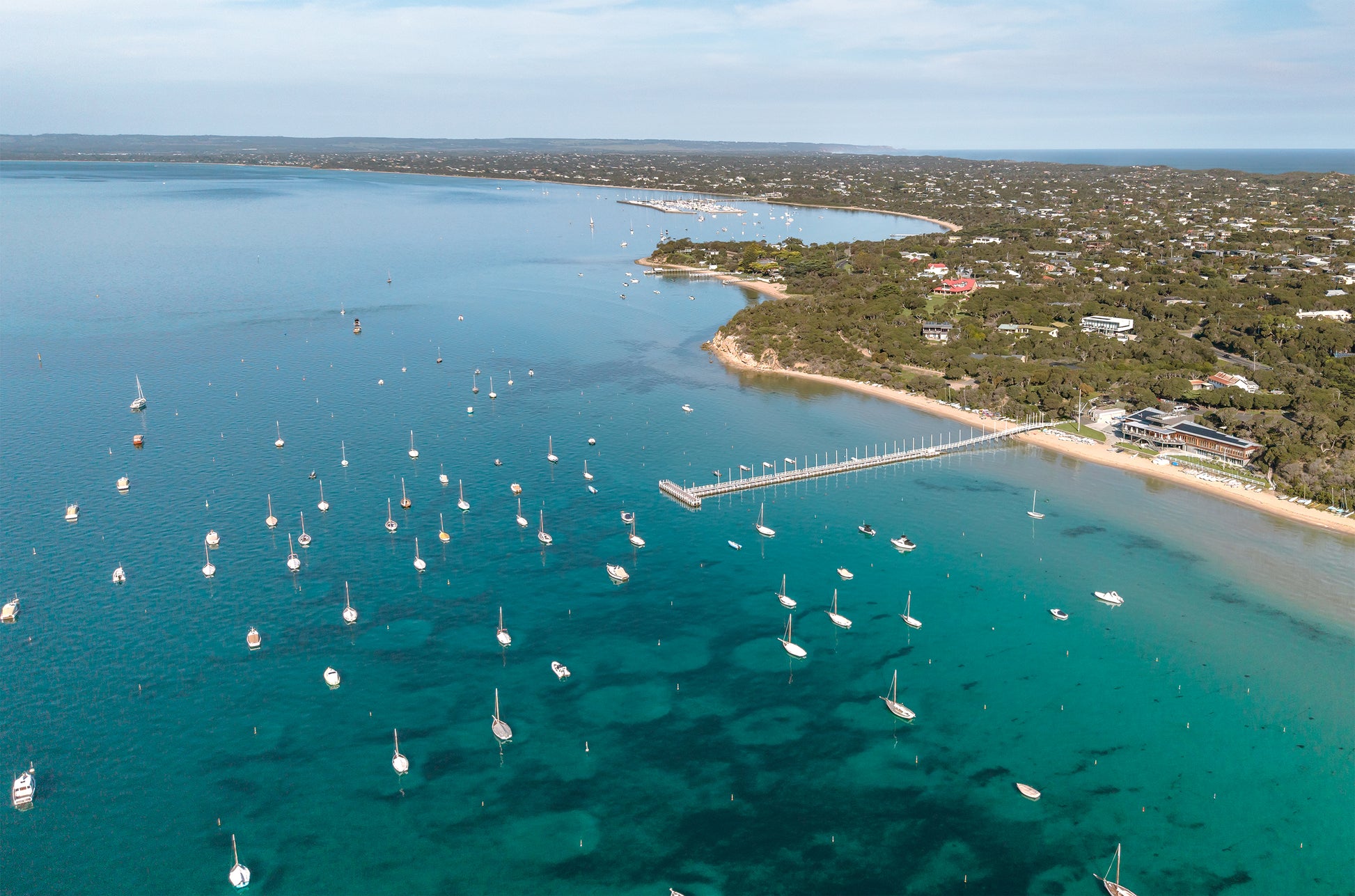 Aerial of Sorrento Front Beach on the Mornington Peninsula VIC, with boats moored on turquoise Port Phillip Bay and the coastline curving toward Blairgowrie.