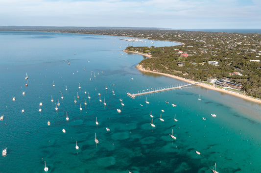 Aerial of Sorrento Front Beach on the Mornington Peninsula VIC, with boats moored on turquoise Port Phillip Bay and the coastline curving toward Blairgowrie.
