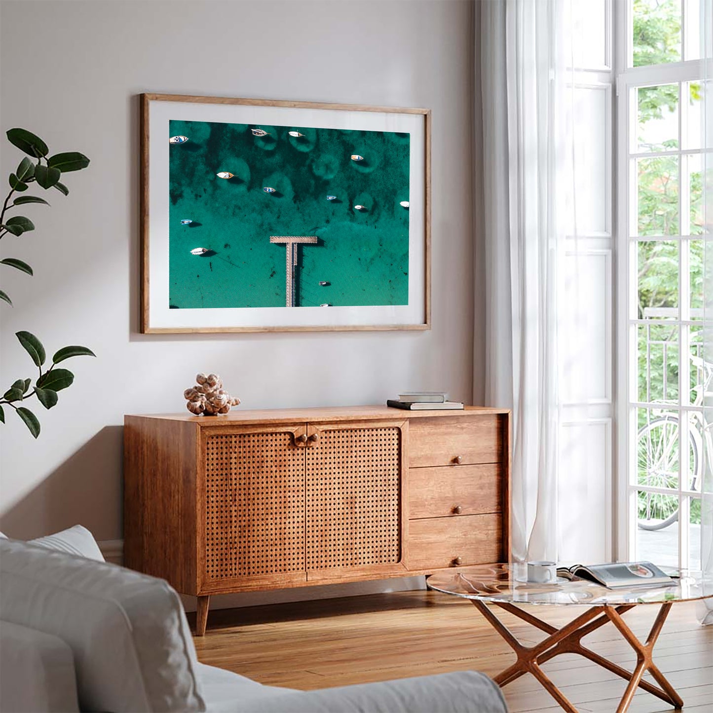 Sorrento Sailing Pier print in a timber frame, styled above a mid-century rattan sideboard beside tall windows.