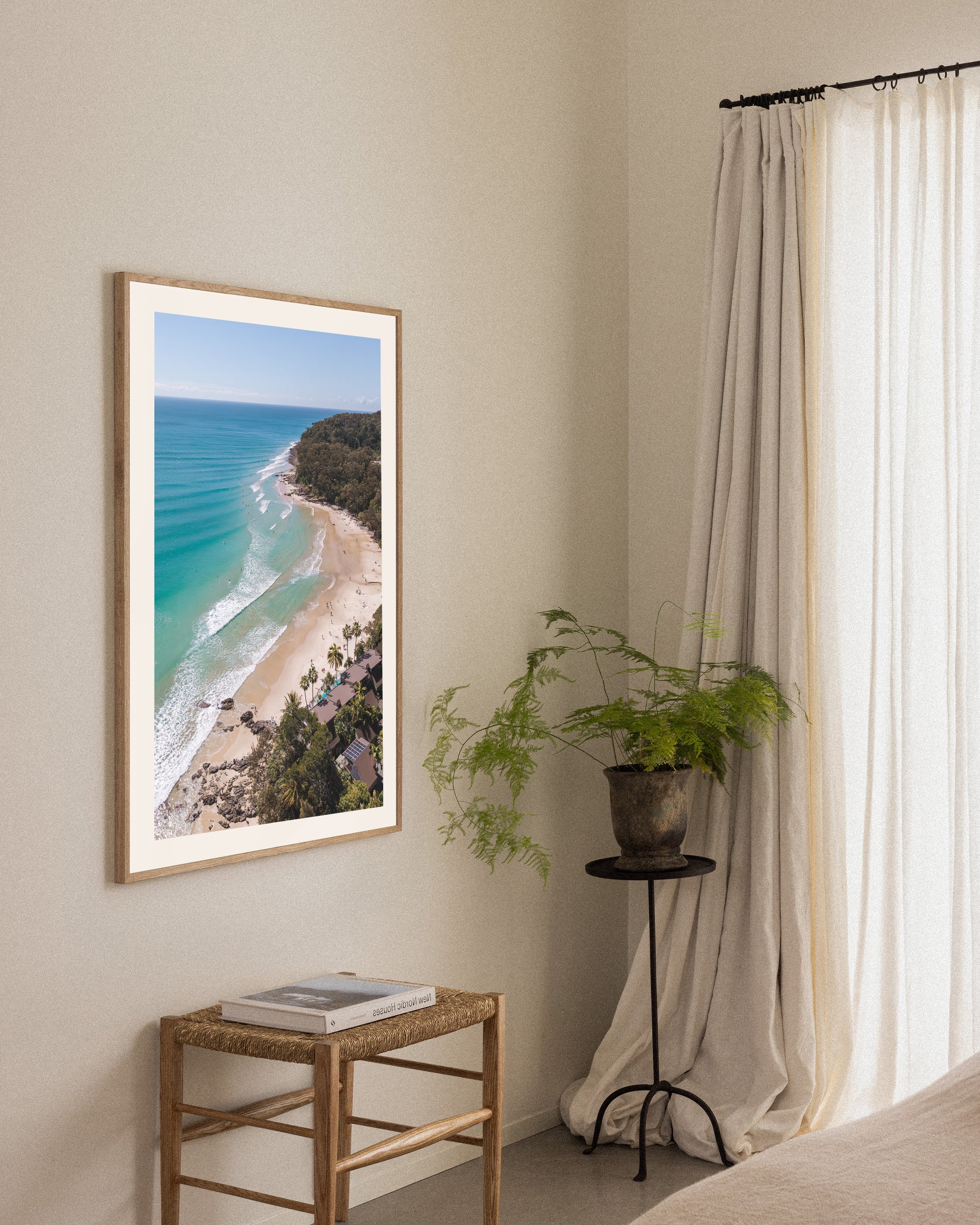 Little Cove Noosa portrait print in a natural oak frame, styled above a small timber stool with a vase beside sheer curtains.